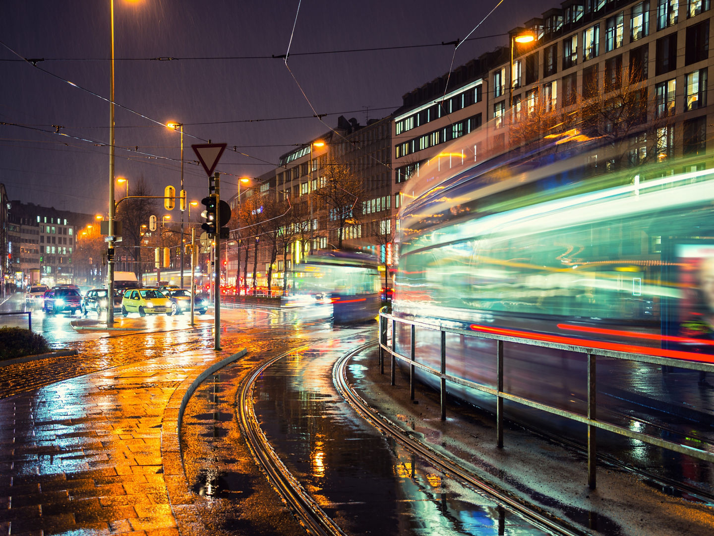 Night in Munich, Germany city center. Motion blurred trams and car traffic. Lights and illumination reflection during the heavy rain.