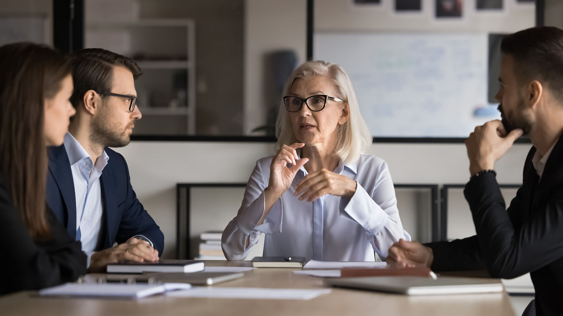 Businesswoman, company boss explains contract details to shareholders, sit at conference table, make speech, provide information, share opinion and strategy, engaged in teamwork activity. Negotiations
