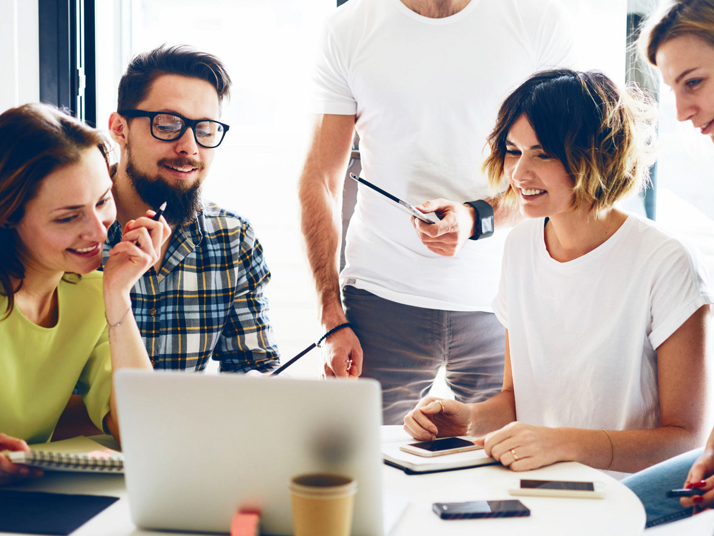 Team of analysts of the modern start up are discussing the business strategy for the next year in the modern and bright office. Young hipsters are sitting with the electronic devices during meeting.