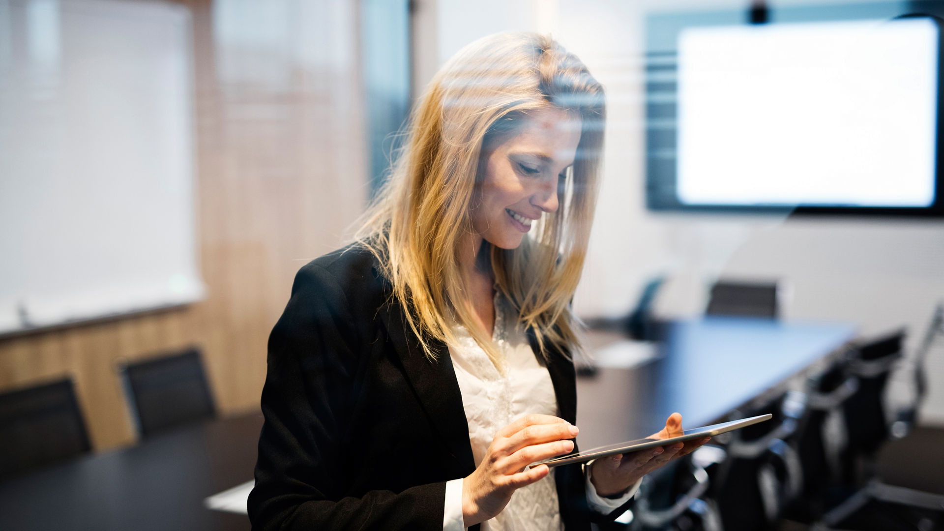 Portrait of beautiful blonde businesswoman holding tablet in conference room
