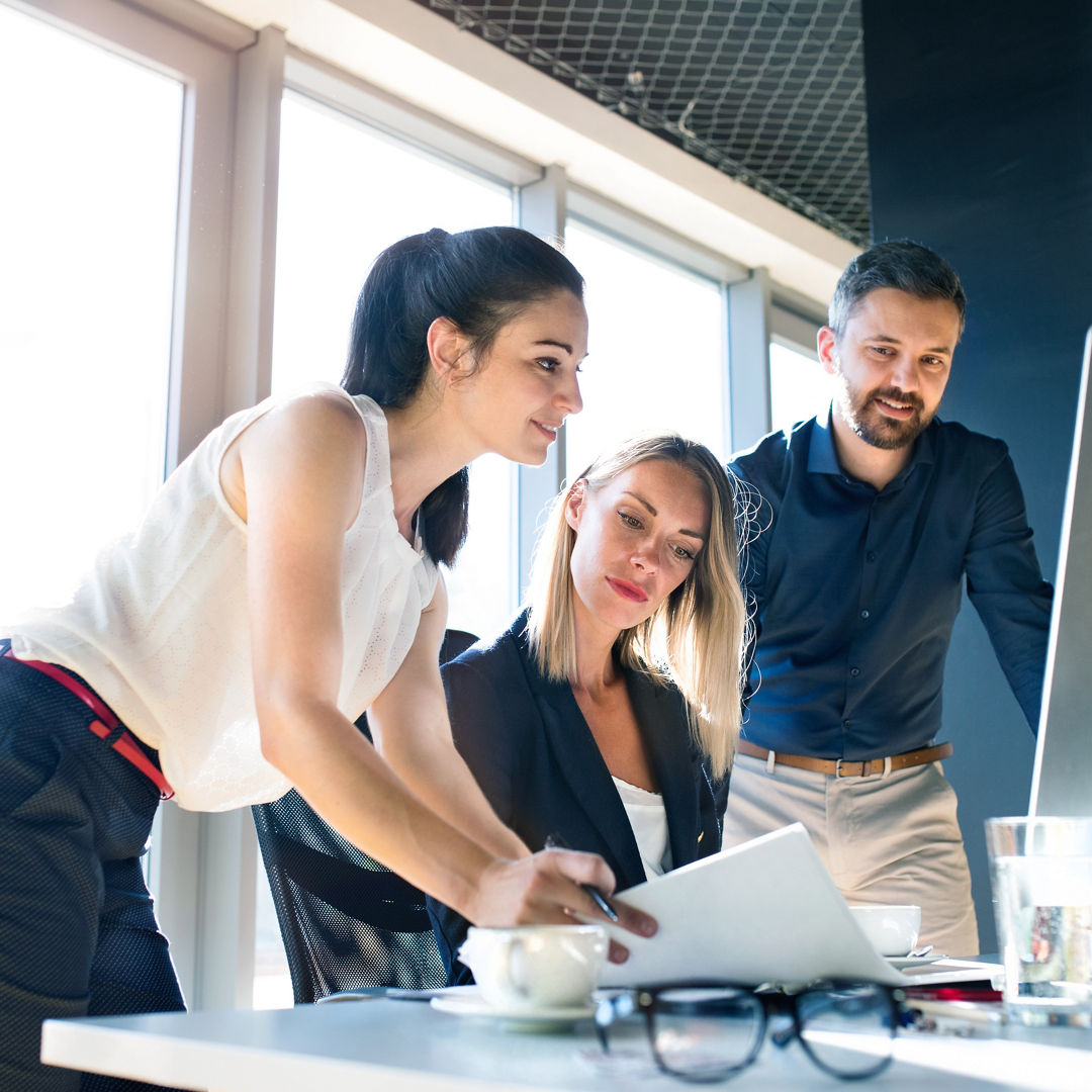 Three attractive young business people in the office working together, consulting a project.