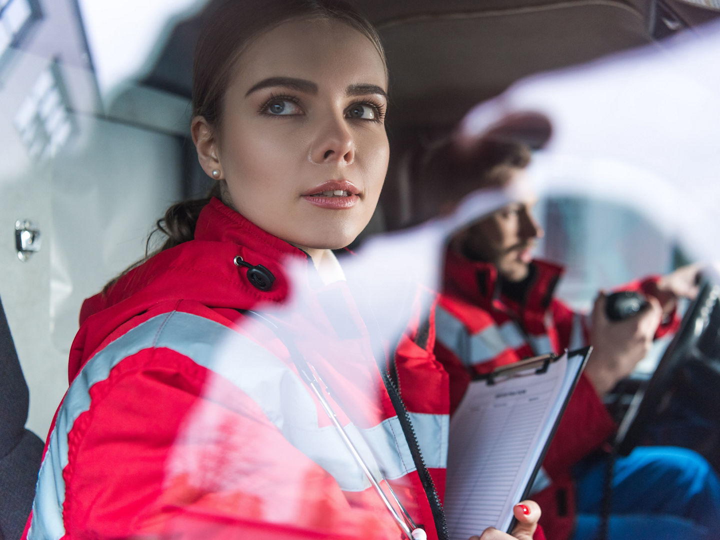 attractive young paramedic sitting in ambulance and looking away