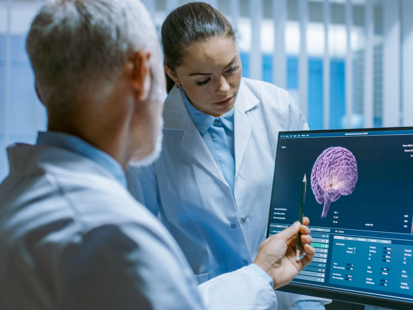 Two Medical Scientists in the Brain Research Laboratory Discussing Progress on the Neurophysiology Project Fighting Tumors. Neuroscientists Use Personal Computer with MRI, CT Scans Show Brain Images.