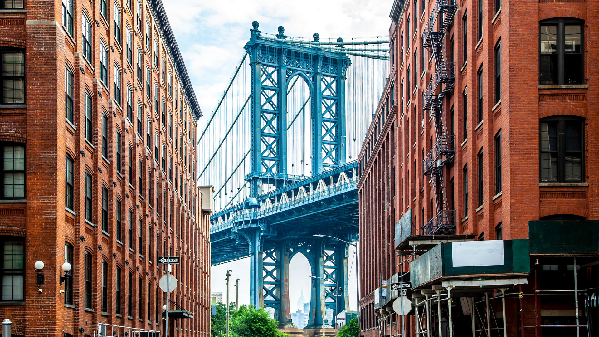 Manhattan Bridge between Manhattan and Brooklyn over East River seen from a narrow alley enclosed by two brick buildings on a sunny day in Washington street in Dumbo, Brooklyn, NYC