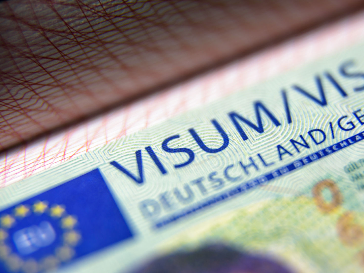 Visa stamp in passport close-up. German visitor visa at border control. Macro view of Schengen visa for tourism and travel in EU. Document for multiple entry. Legal immigration to Germany and Europe.