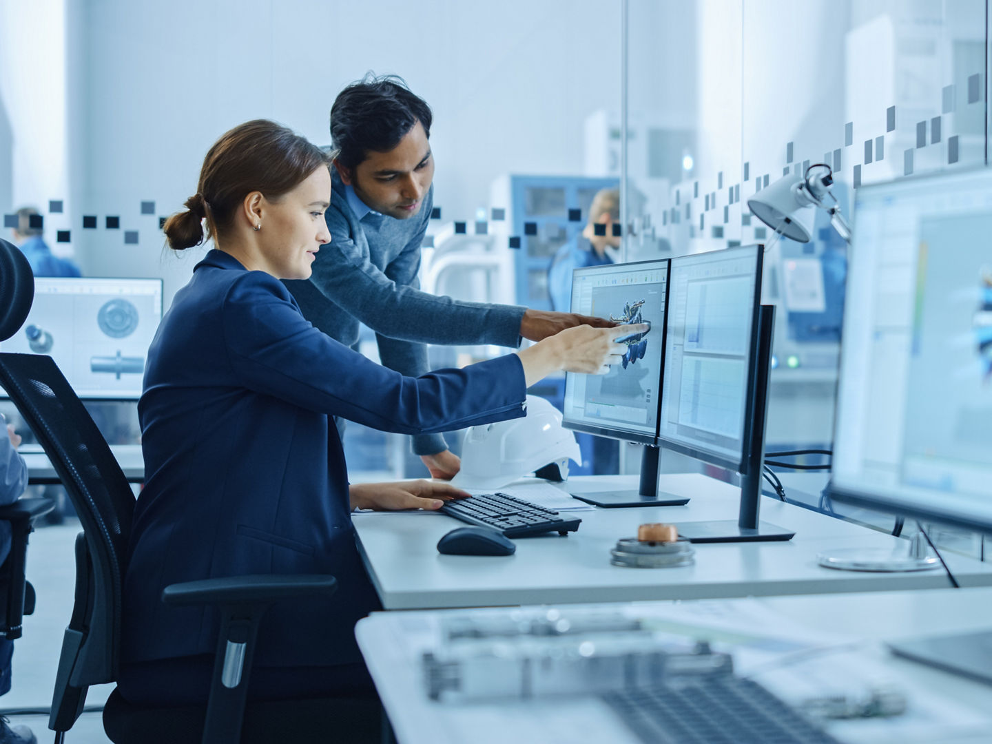 Inside Factory Office: Male Project Supervisor Talks to a Female Industrial Engineer who Works on Computer, Talk. In Workshop: Professional Workers Use High-Tech Industry 4 CNC Machinery, Robot Arm.