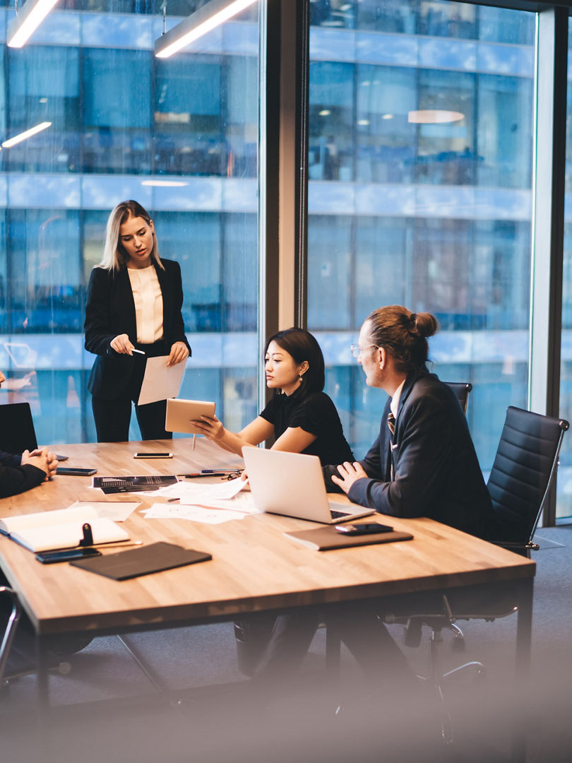 From above of multiethnic executive managers in classy outfit gathering at table and sharing ideas during meeting in modern workplace