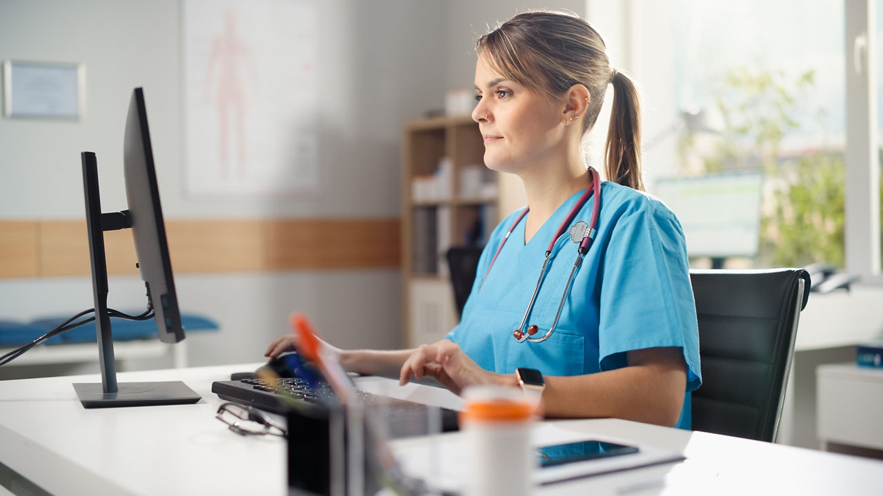 Hispanic Doctor's Office: Experienced Head Nurse Sitting at Her Desk Working on Personal Computer. Medical Health Care Specialist Filling Prescription Forms, Checking Analysis Test Results.