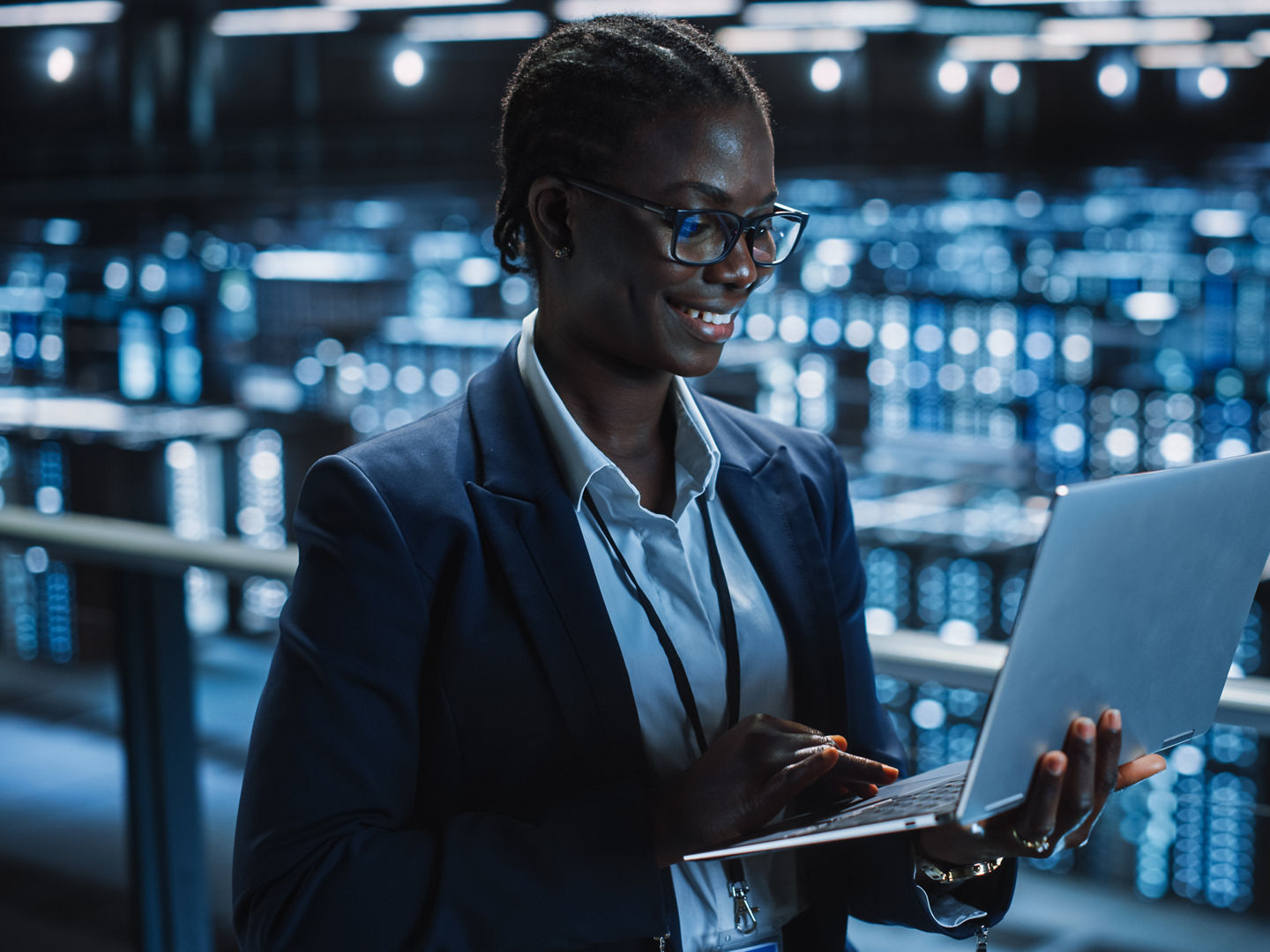 Data Center Female Programmer Using Laptop Computer, Maintenance IT Specialist. In Cloud Computing Server Farm Smiling System Administrator Working on Cyber Security for Iaas, saas, paas.