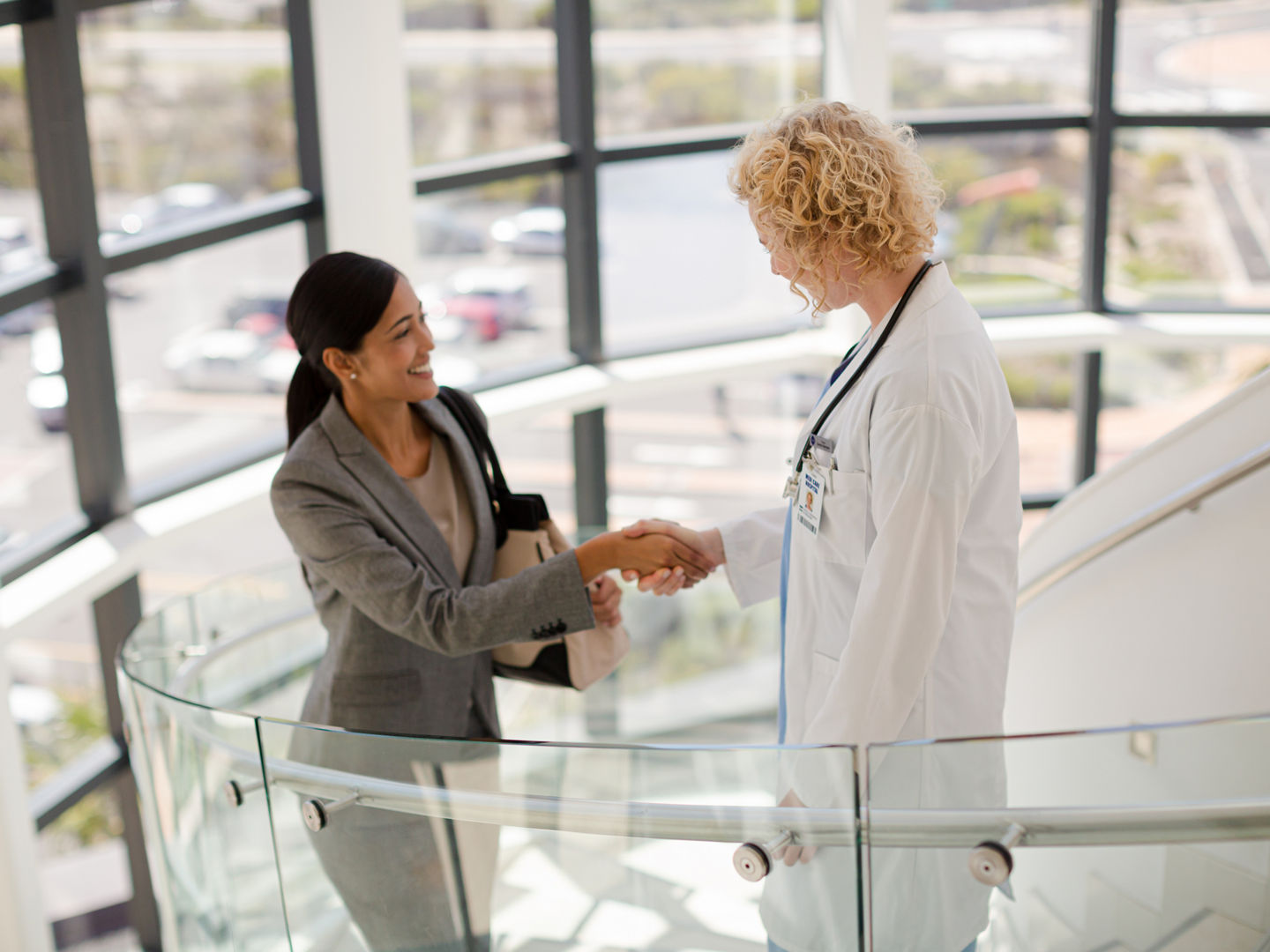 Doctor and businesswoman handshaking on stairs in hospital