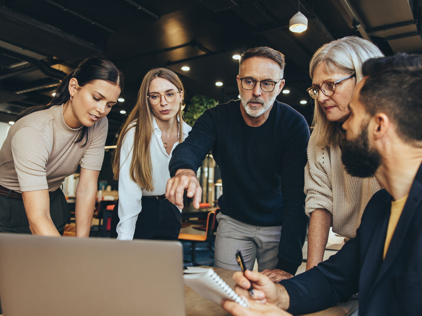 Focused businesspeople having a discussion while collaborating on a new project in an office. Group of diverse businesspeople using a laptop while working together in a modern workspace.