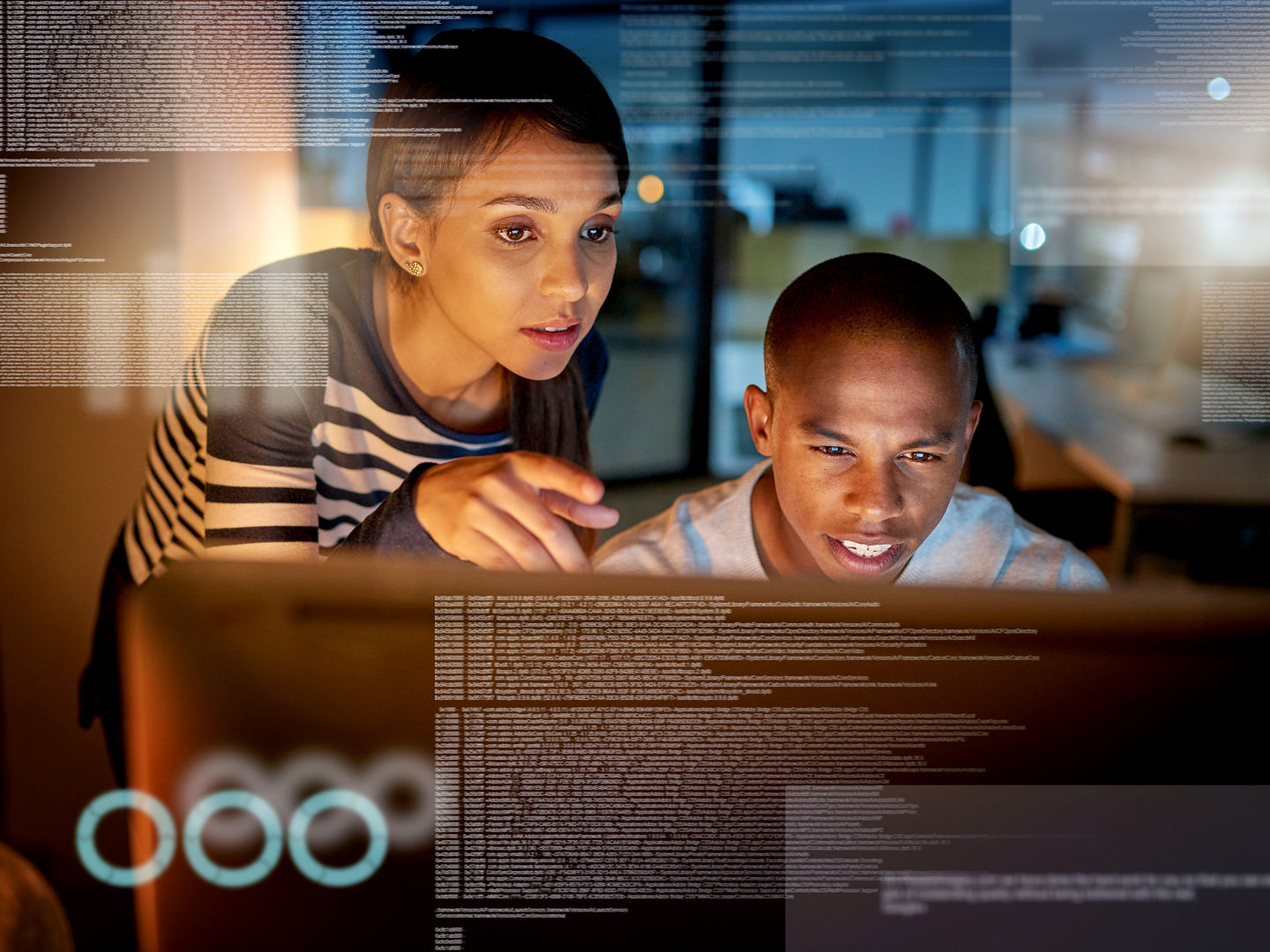 Shot of colleagues connecting to a user interface while working in an office at night.