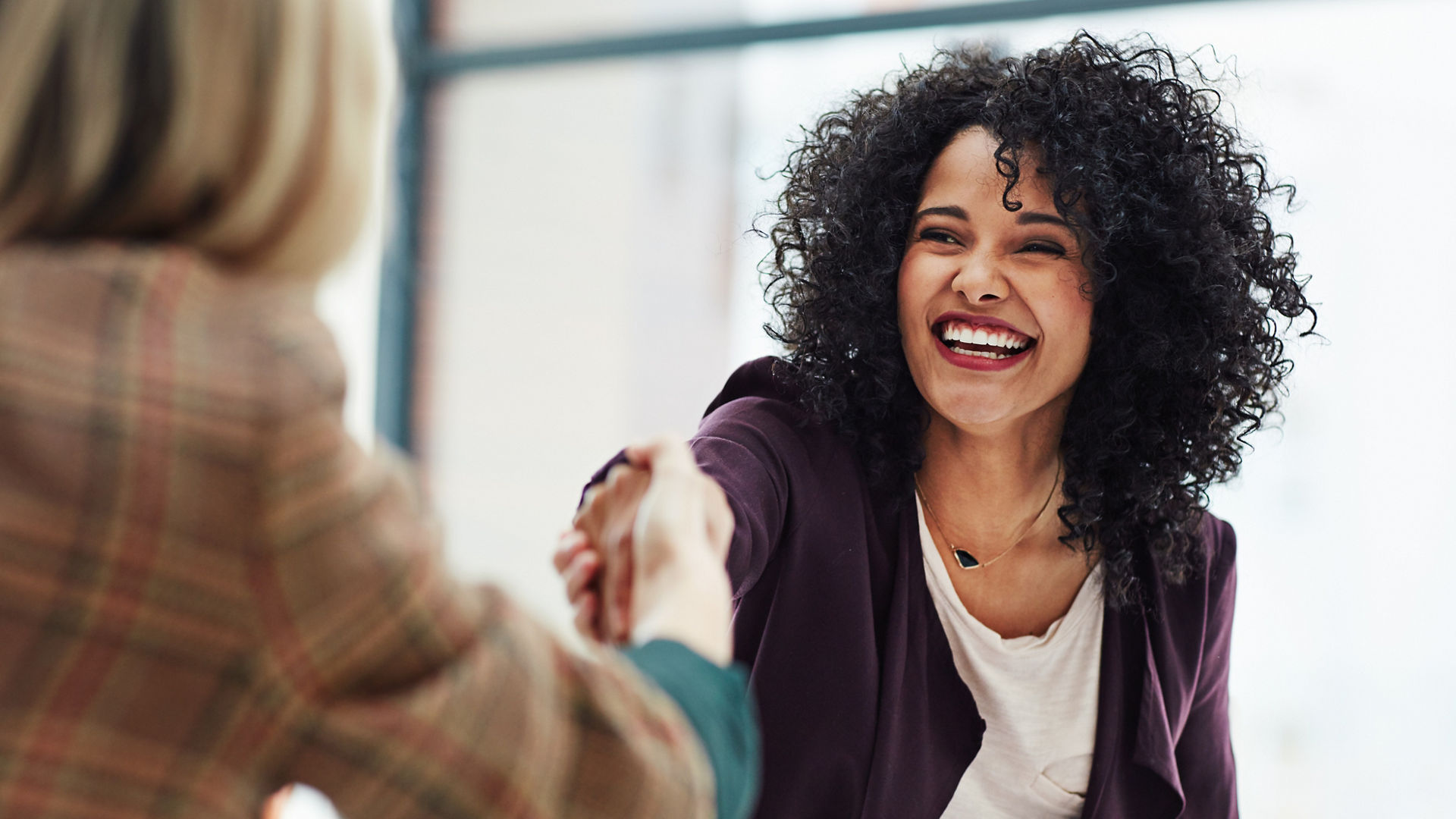 Handshake with a happy, confident and excited business woman or human resources manager and a female colleague, partner or employee. An agreement, deal or meeting with a coworker in the boardroom.