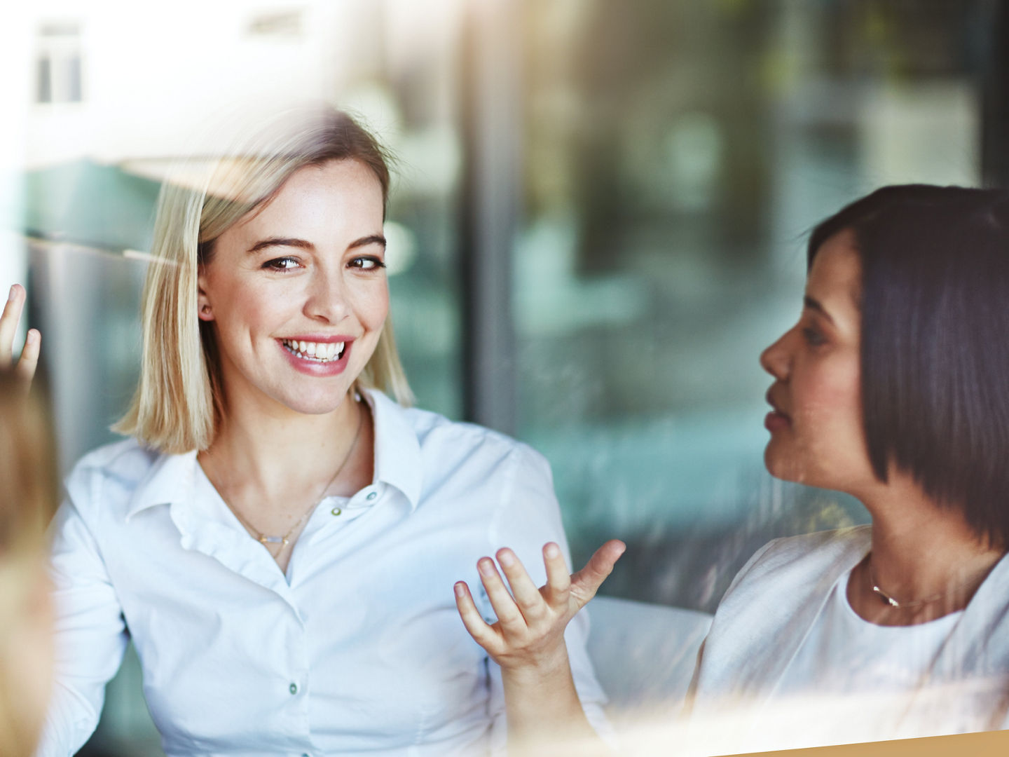 Female office worker on a break with colleagues talking and having a conversation at work. Business people spending time together inside. Smiling corporate business woman with team indoors.