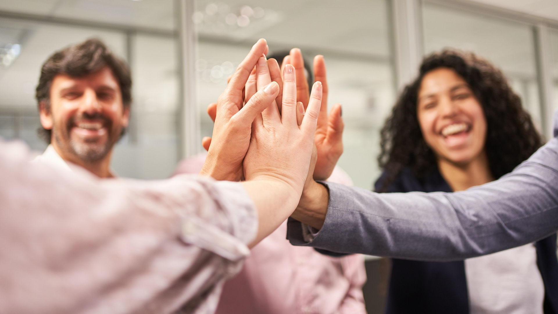 Junge Geschäftsleute im Startup Team beim High Five für Zusammenarbeit und Teamgeist