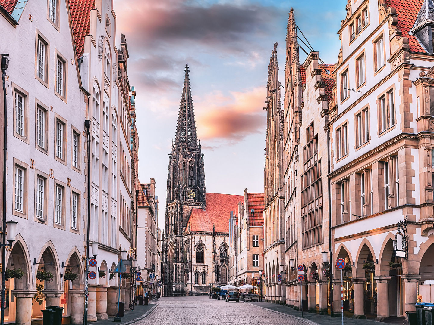 Scenic sunset view of Prinzipalmarkt square in Munster, Germany - without crowds of tourists at famous shopping street and tourist attraction. Saint Lamberti Tower at background.