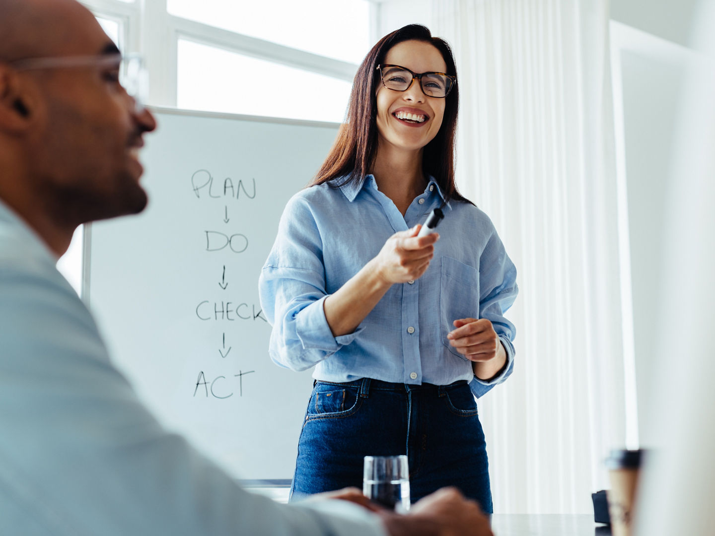 Happy business woman discussing ideas with her team during a meeting. Young business woman giving a presentation in an office.