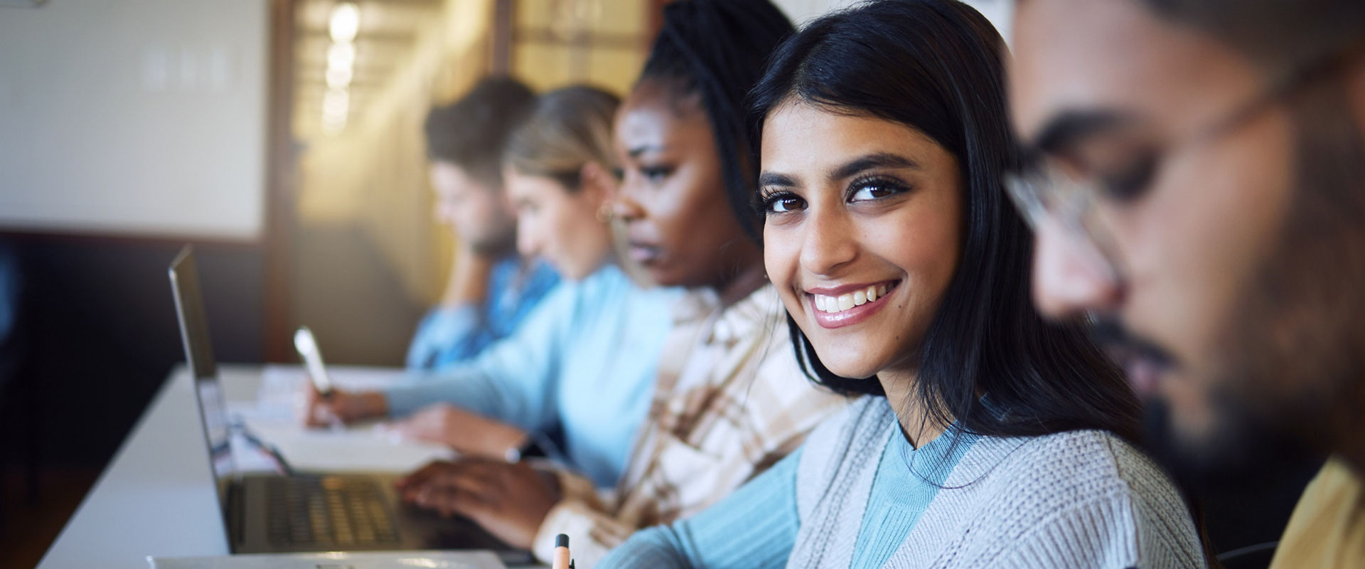 College student writing notes for business management in classroom, course and campus. Portrait, young indian girl and university student happy for learning, education and studying at finance academy.