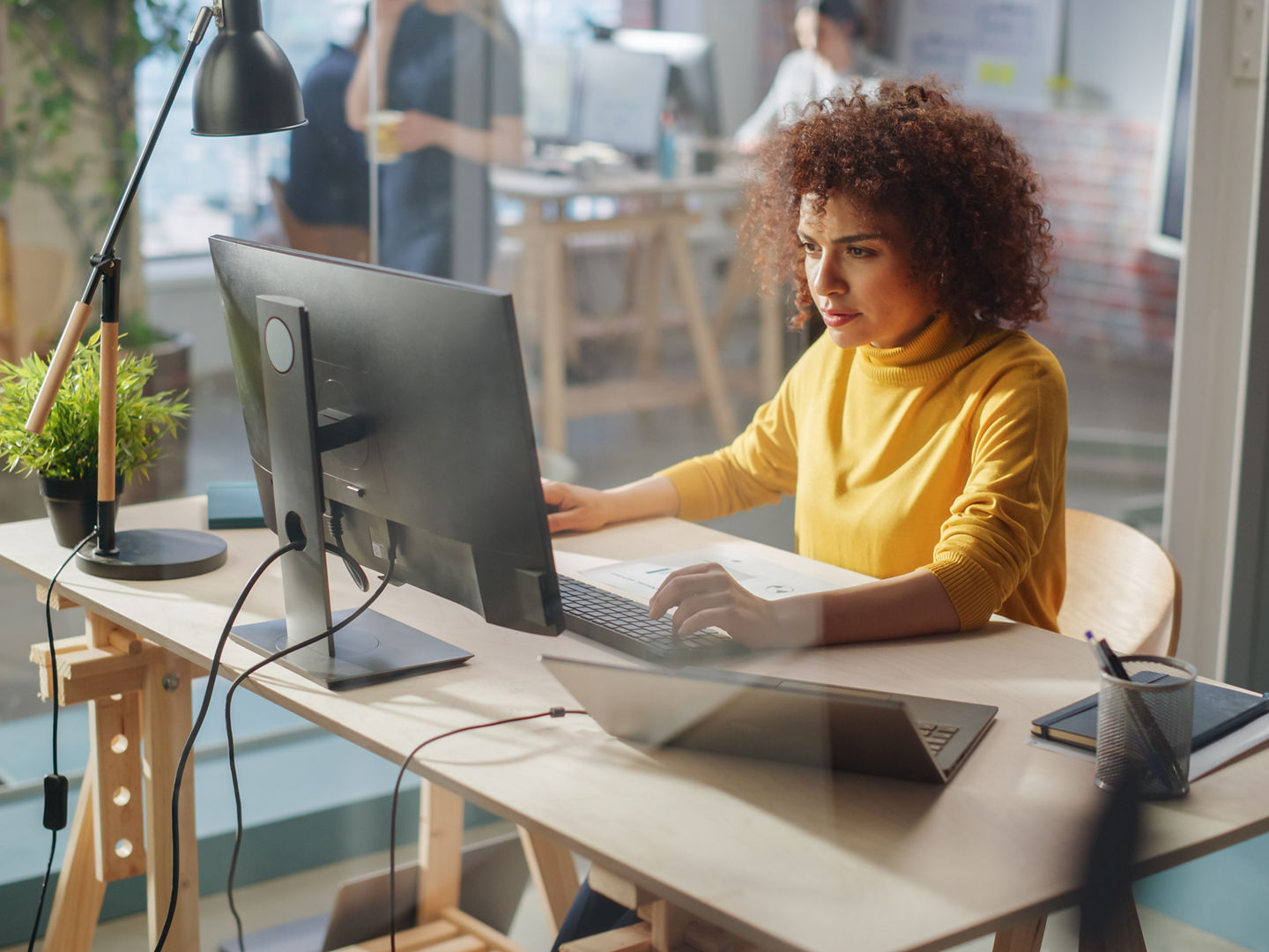 Creative Multiethnic Female Working on Computer with Two Displays in an Office. Happy Project Manager Browsing Internet, Writing Tasks, Developing a Marketing Strategy for a Corporate Partner., Creative Multiethnic Female Working on Computer with Two Display