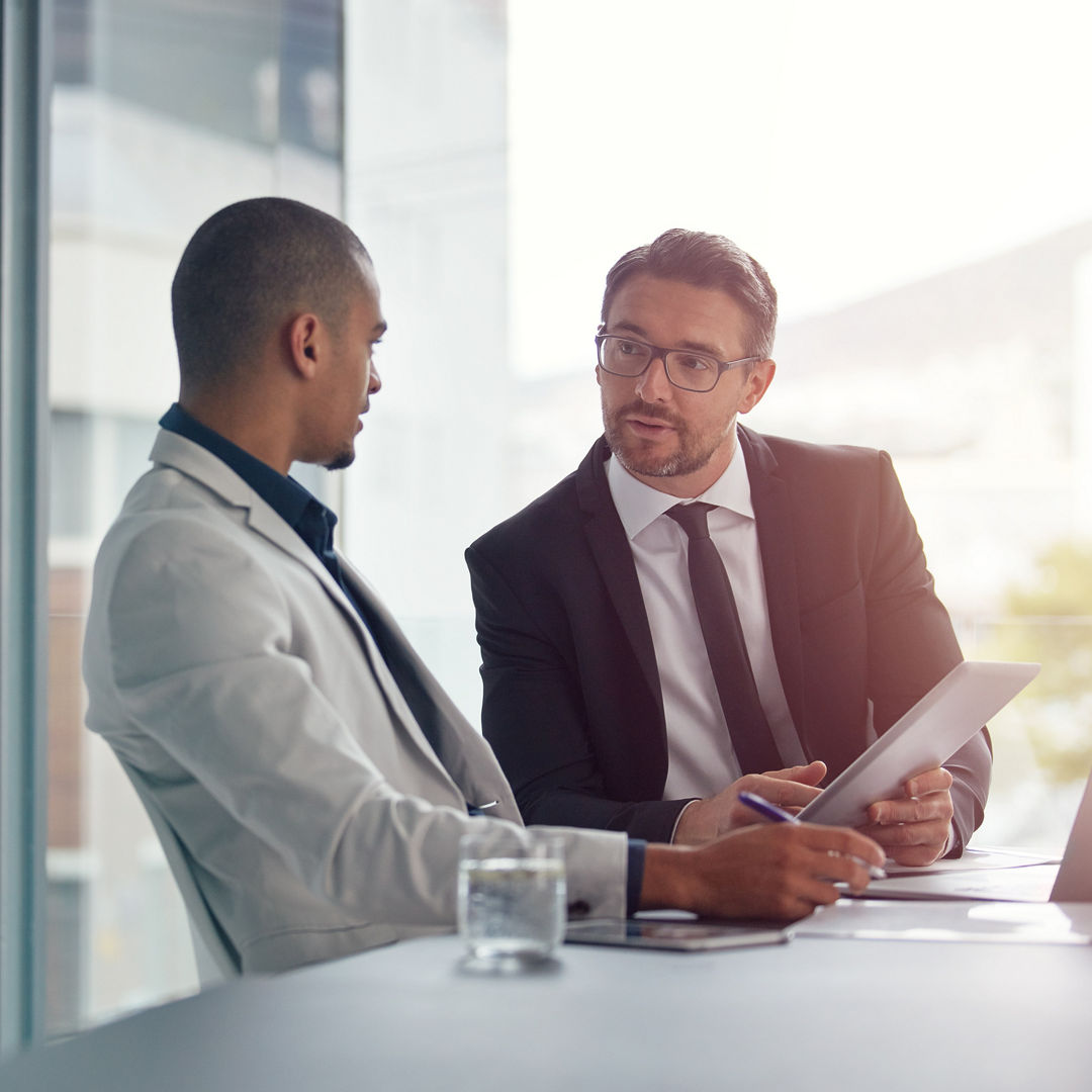 Business. partner, planning and meeting with tablet for corporate strategy for online marketing. Men in a management discussion or consulting at table using internet for ideas, talking and teamwork.