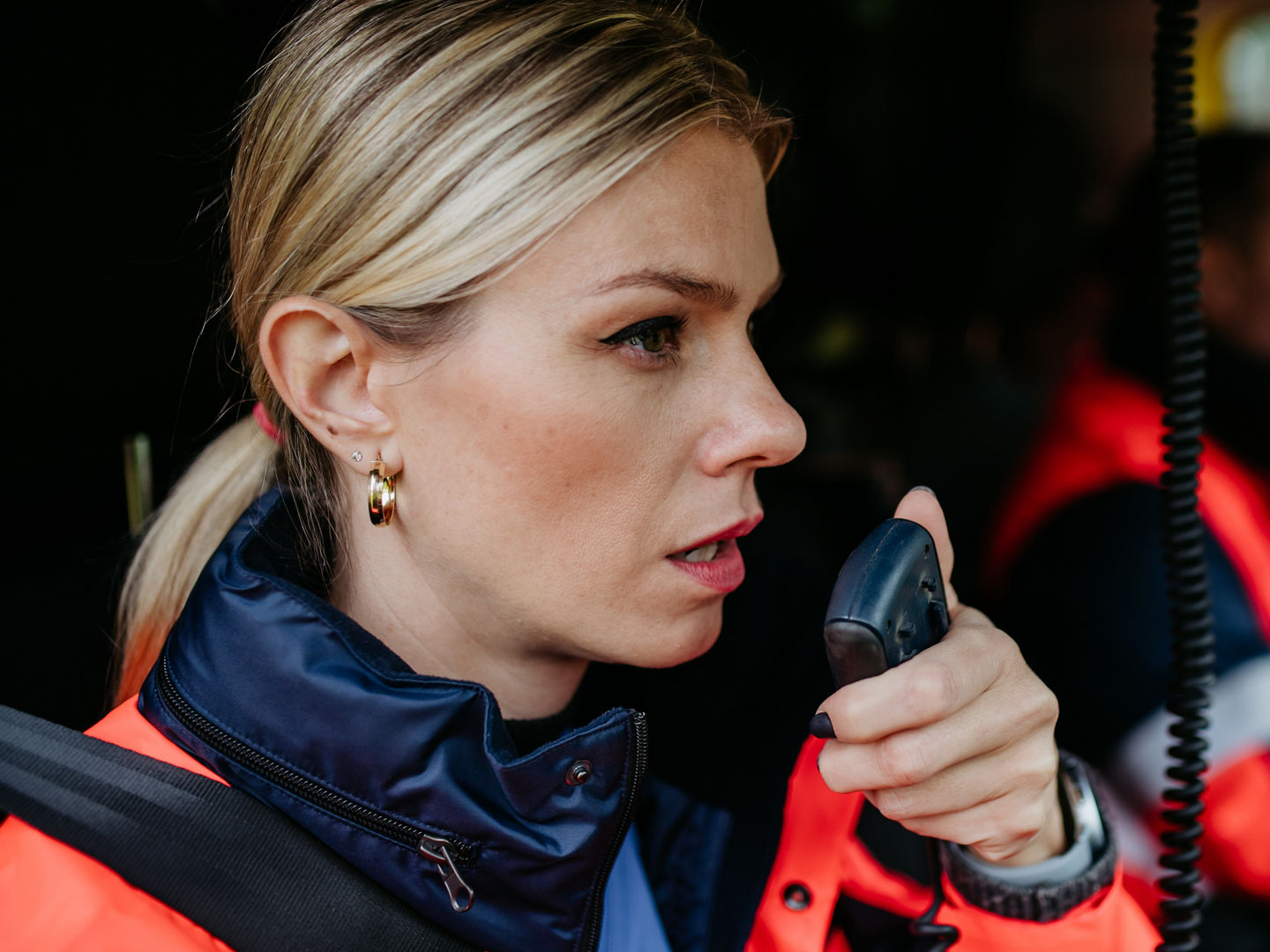 Portrait of a young woman doctor sitting and talking in to walkie-talkie in ambulance car.