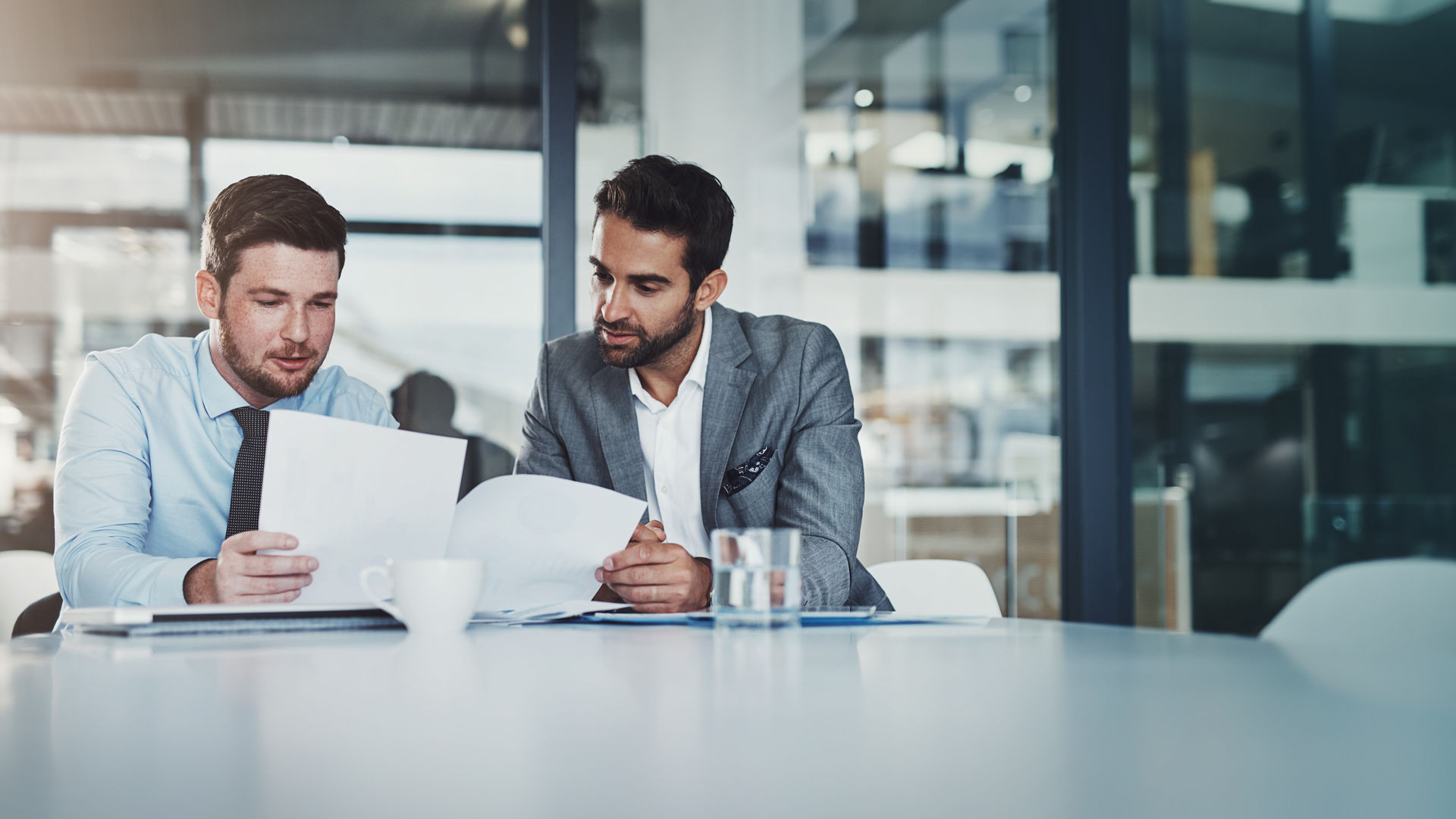 Meeting, documents and businessmen in discussion in the office boardroom planning a corporate strategy. Brainstorming, collaboration and male employees working on project with paperwork in workplace