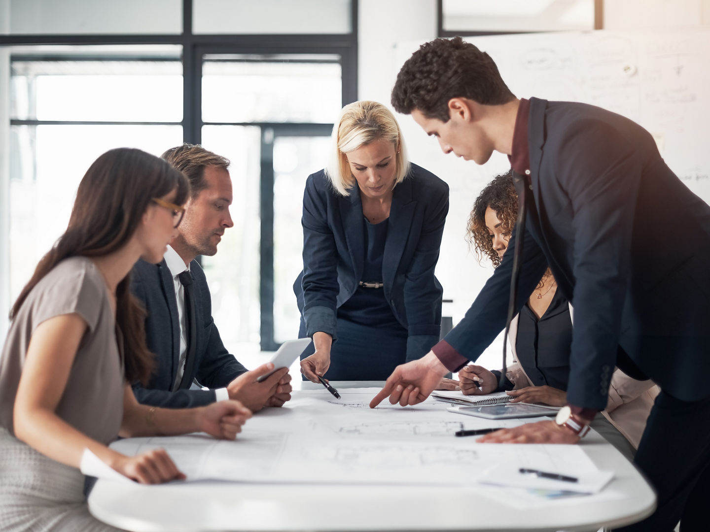 Business people, architect and blueprint in meeting, brainstorming or planning for strategy at the office. Group of contract engineers in teamwork, floor plan or documents for industrial architecture.