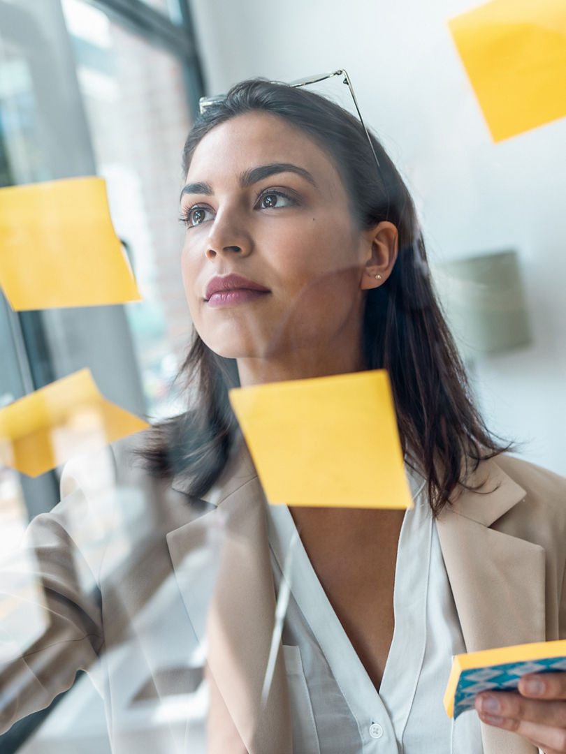 Shot of elegant beautiful businesswoman working on wall glass with post it stickers in the office