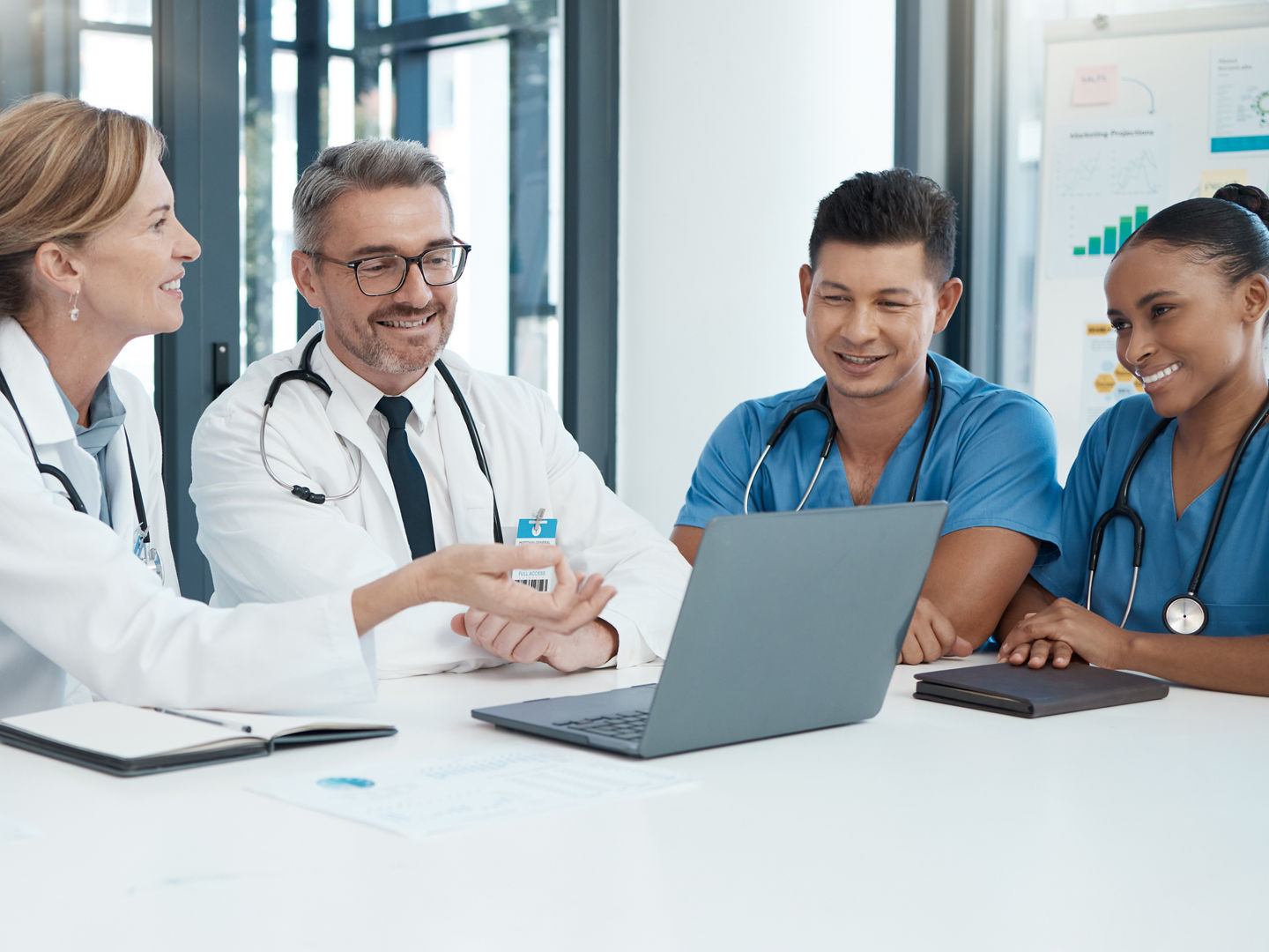 Doctor with laptop, team and health, meeting and professional collaboration on medical innovation and healthcare policy. Teamwork in conference room, diversity and group discussion at the clinic