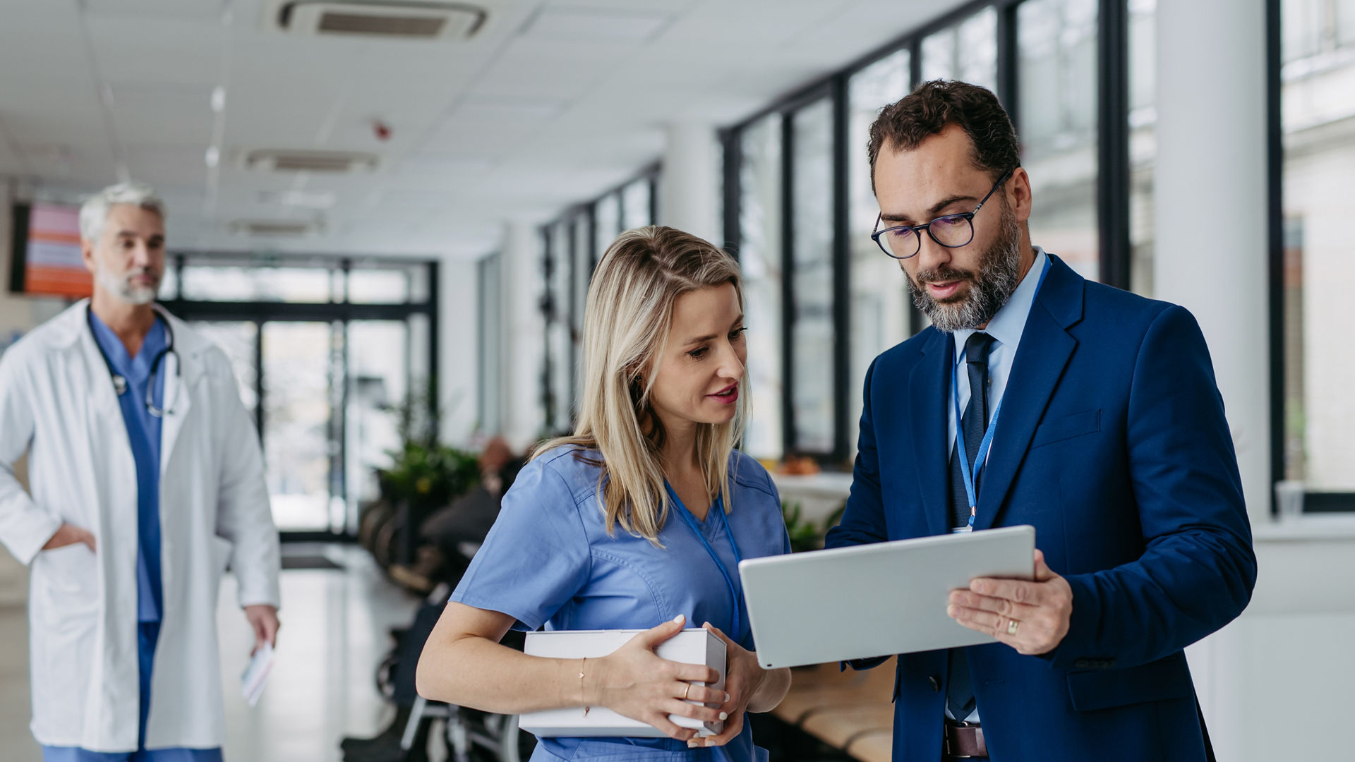 Pharmaceutical sales representative presenting new product to doctors in holding box with pills. Presenting new pharmaceutical product, drugs, medication.Hospital director, manager in private medical clinic showing something on tablet.