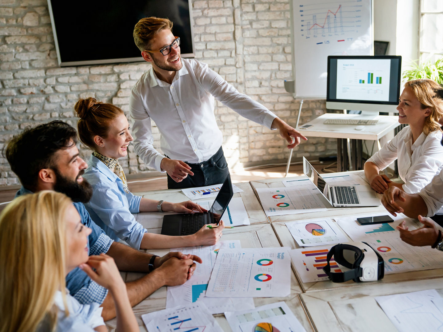 Diverse employees gathered in the office having fun during brainstorming while discussing new ideas for their new project. Multiracial coworkers gather in boardroom discuss ideas in group at briefing.