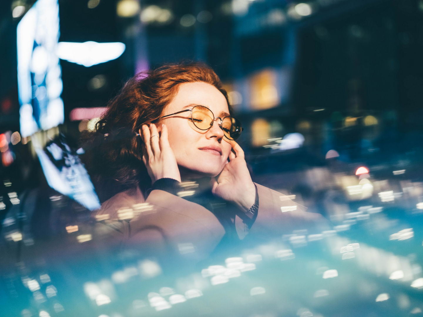 Woman enjoying nightlife and listening music in earphones at neon city illumination