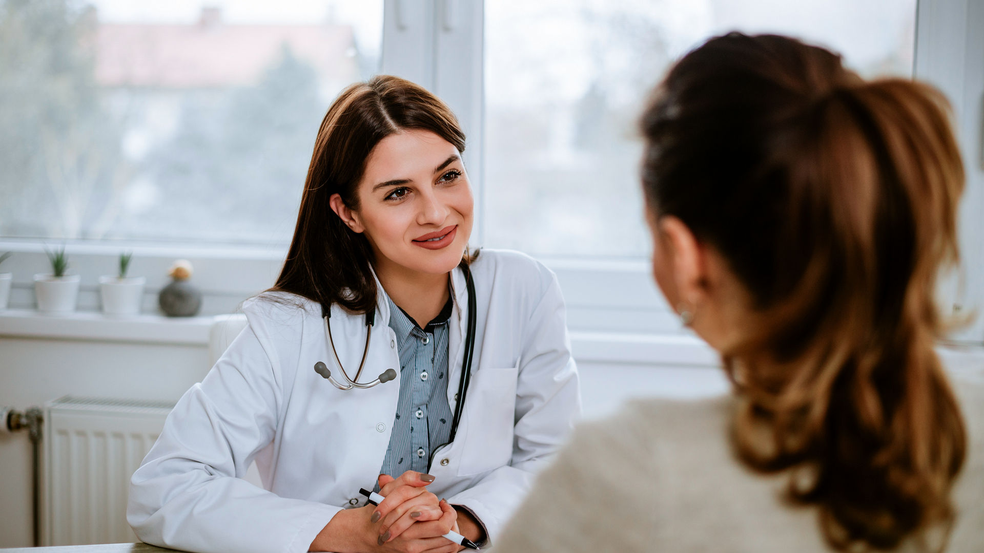 Cheerful young doctor listening to a patient in the office. 