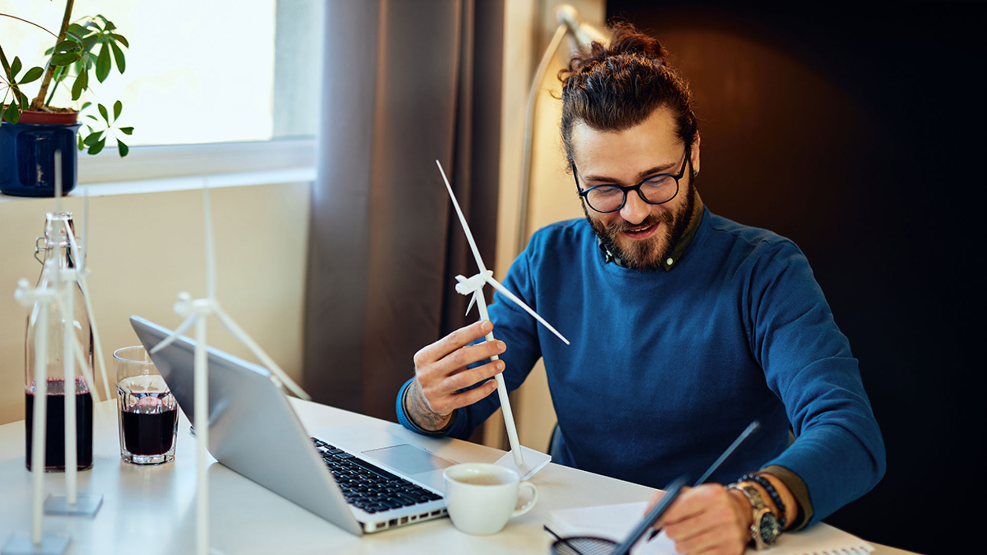 Attractive bearded environmentalist sitting in his office and drawing new windmill model.