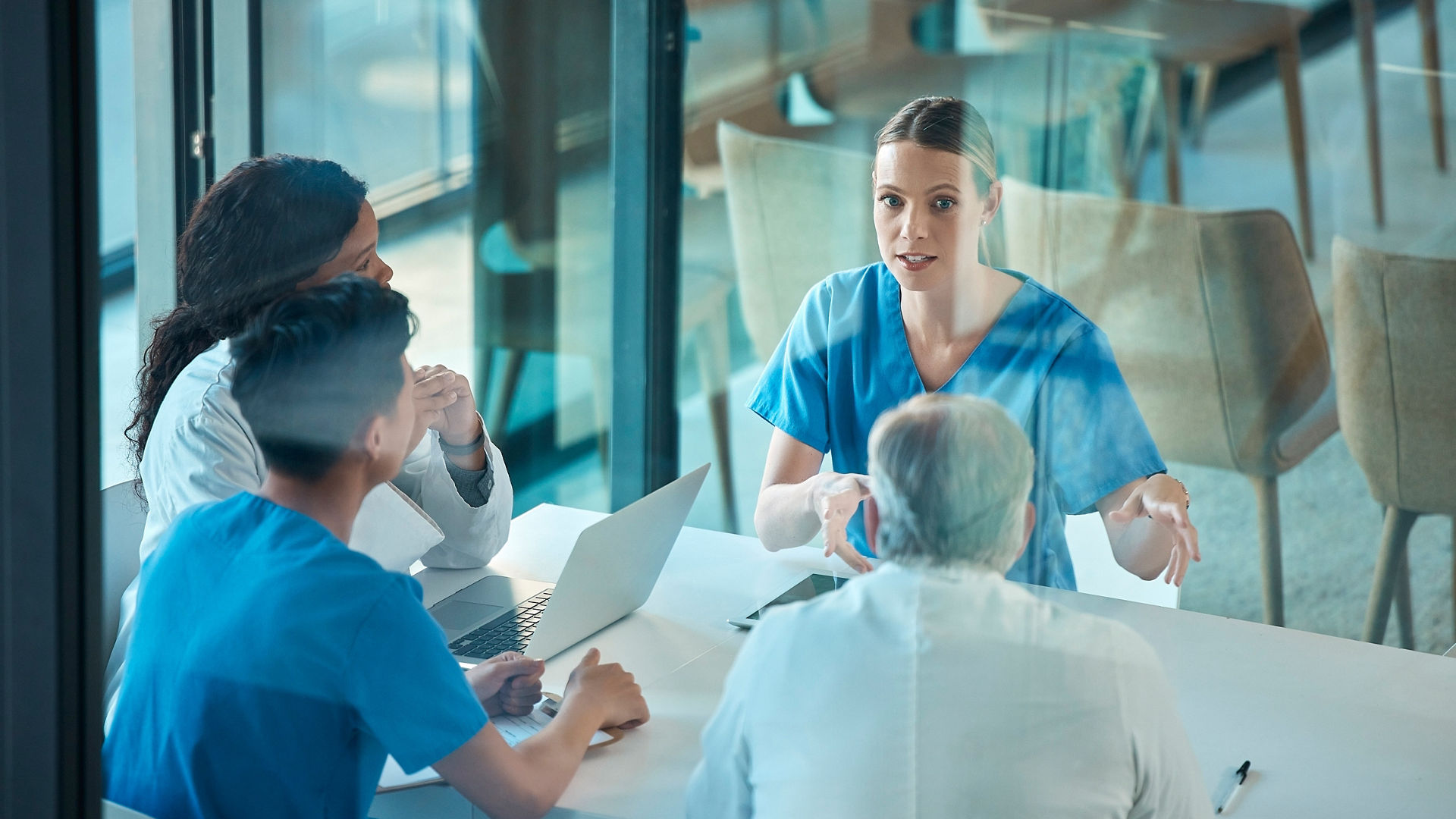 Medical team, doctors and meeting with a laptop for a discussion, planning or research at table. Men and women healthcare group talking about communication strategy, virus or surgery in a hospital.