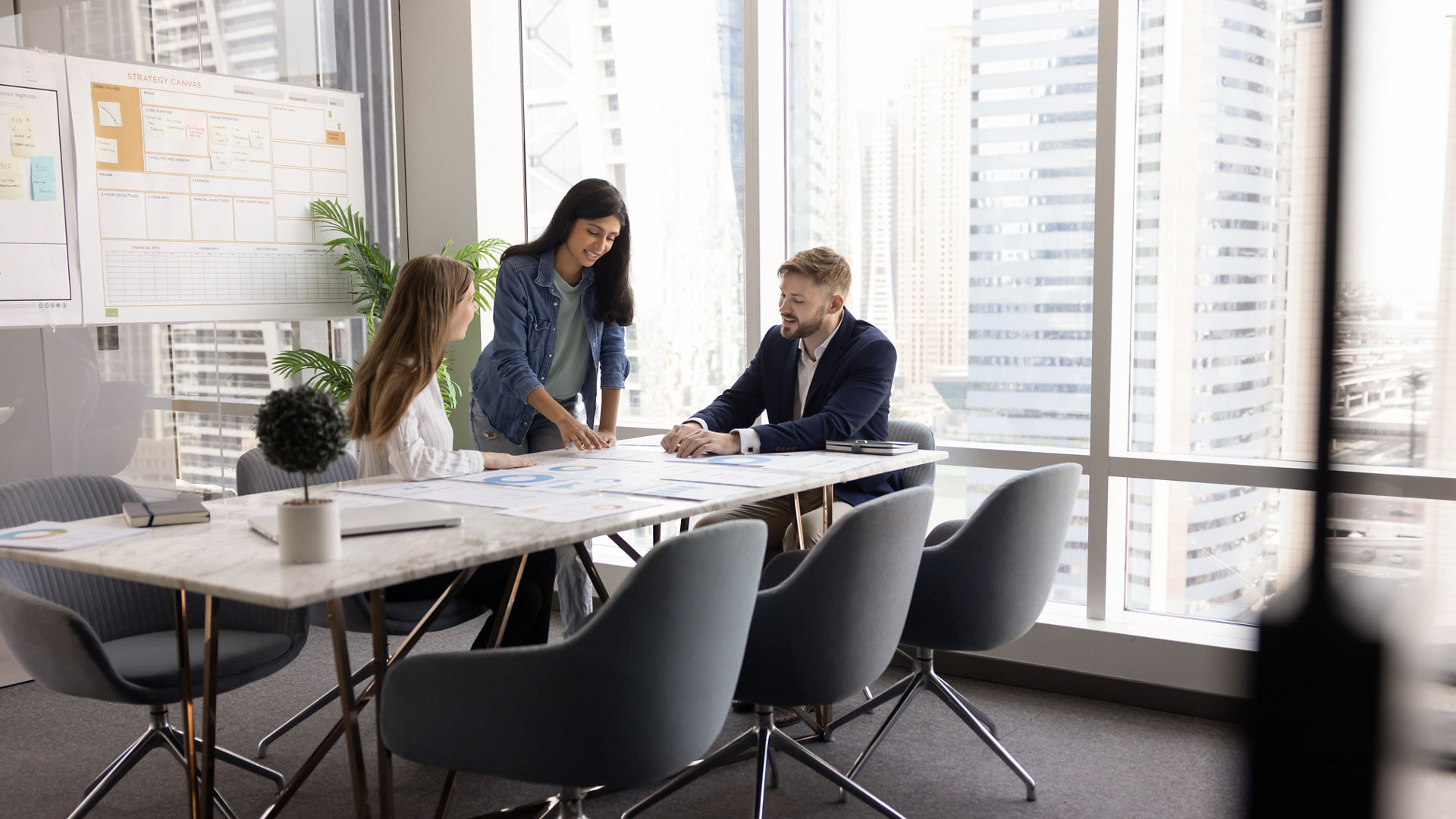 Group of startup founders gathered around conference table, collaborating on business plan and pitch decks, reviewing market strategies, working together on financial forecast, analyzing sales data