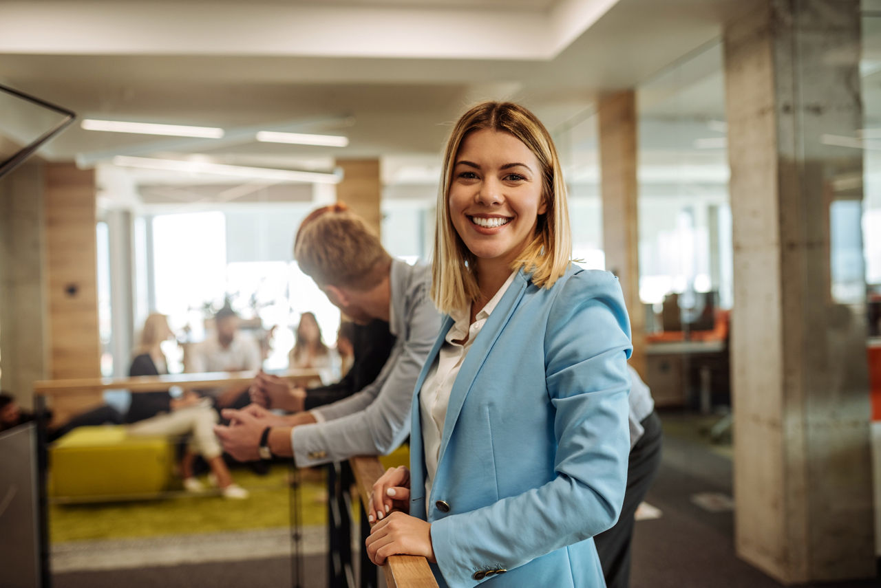 Portrait of a smiling young business woman surrounded by colleagues in the office.