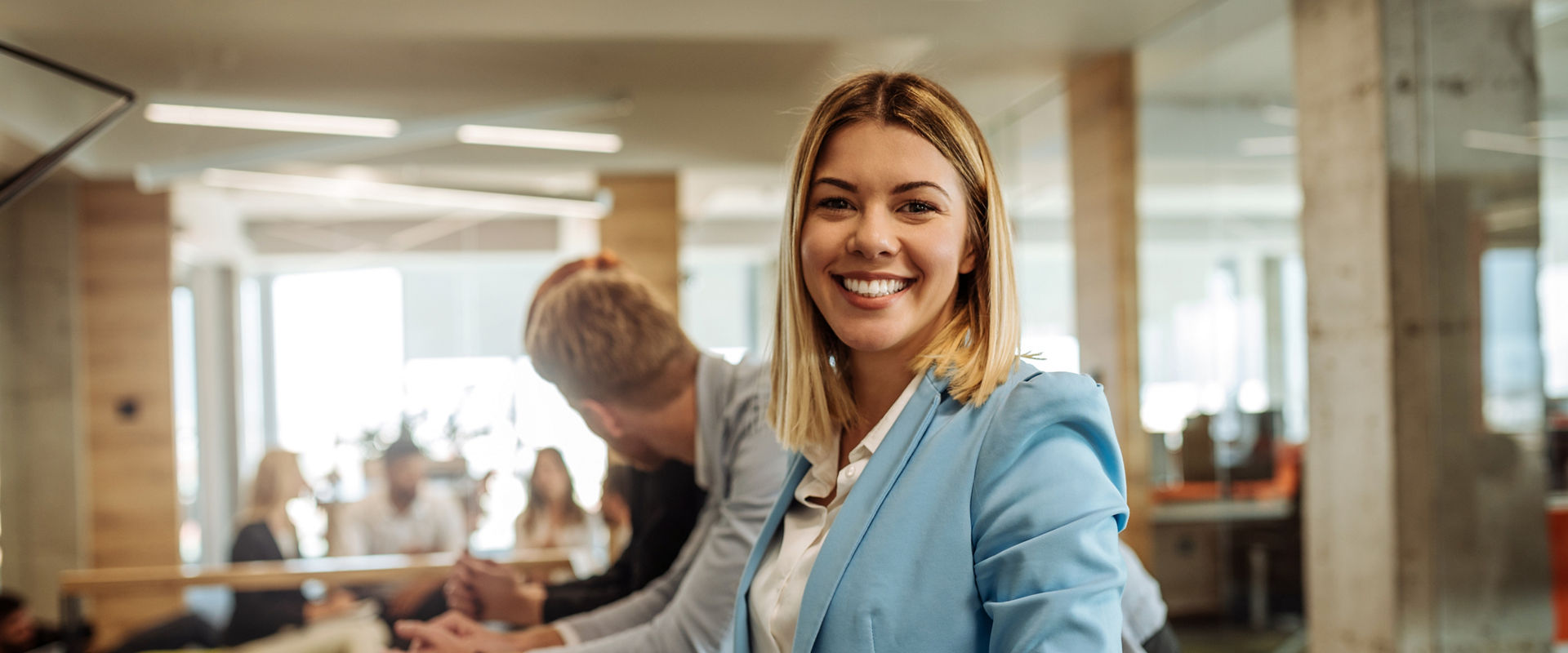 Portrait of a smiling young business woman surrounded by colleagues in the office.