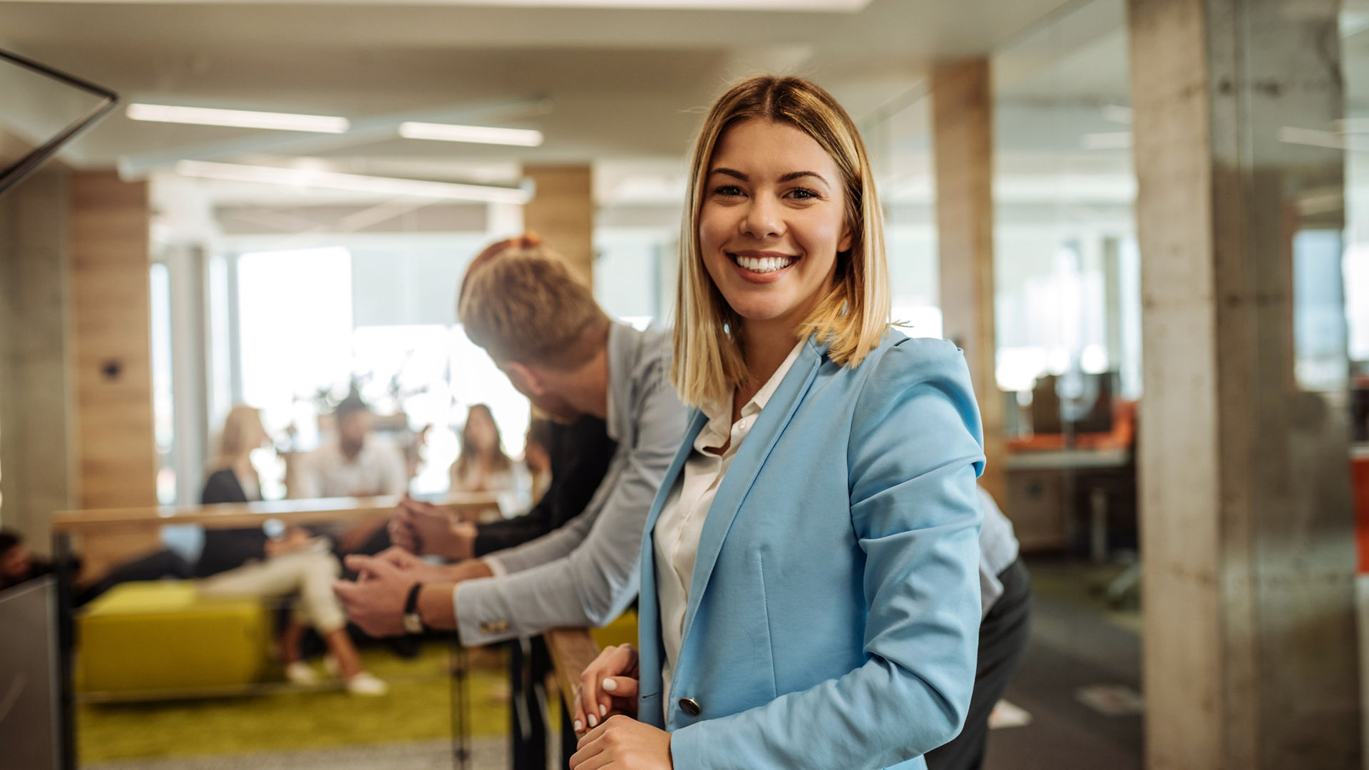 Portrait of a smiling young business woman surrounded by colleagues in the office.